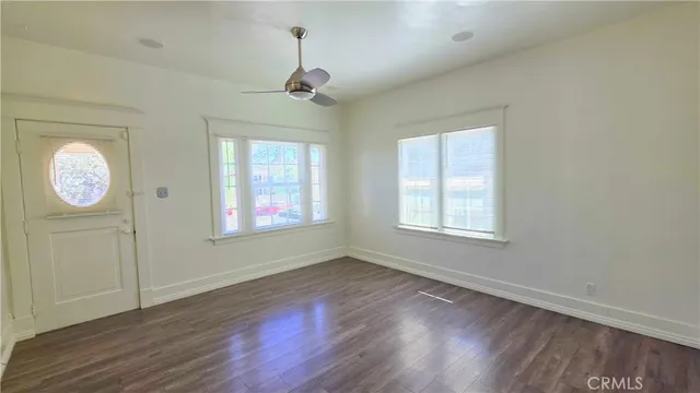 a view of an empty room with a window and wooden floor