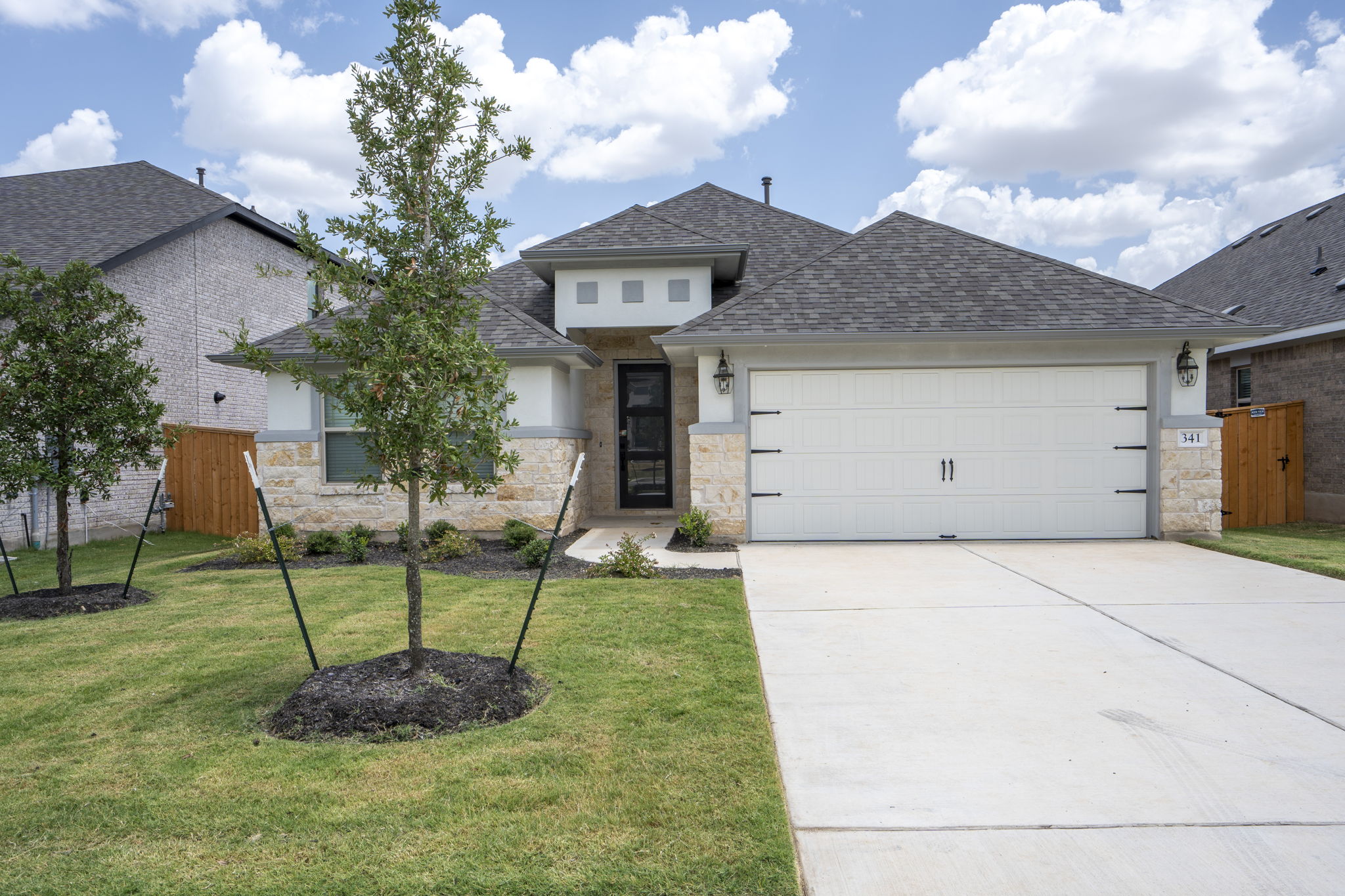341 Fawn Riv Run Kyle, TX 78640 - Photo 1 of 29 View of front of home featuring an attached garage, stone siding, driveway, a front yard, and a shingled roof