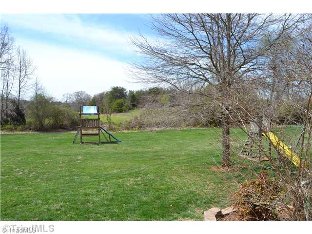 7497 Bethel View Court Oak Ridge, NC 27310 - Photo 16 of 16 Exterior Back. LARGE OPEN YARD WITH PLAYSET