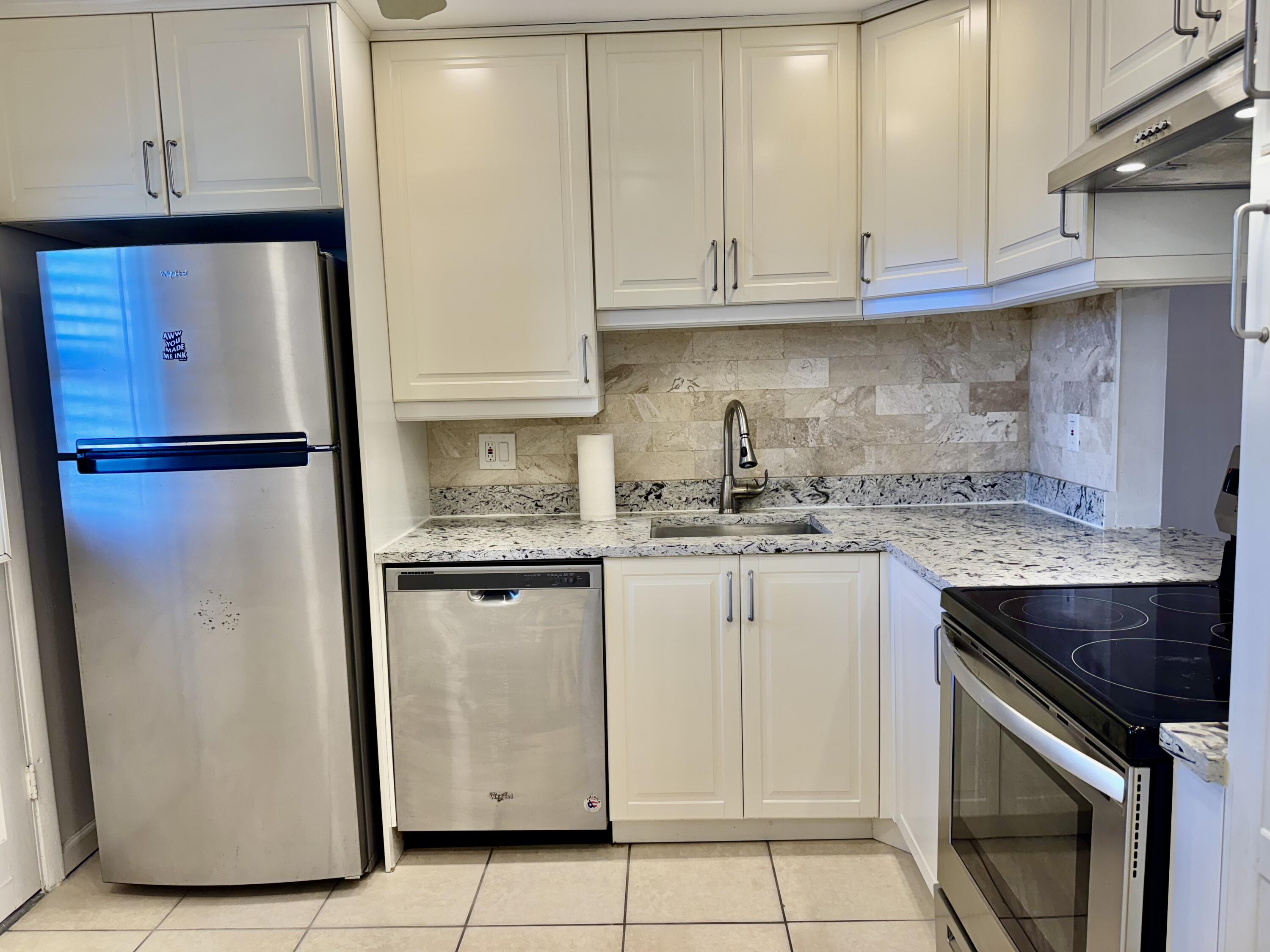 a kitchen with granite countertop white cabinets and stainless steel appliances