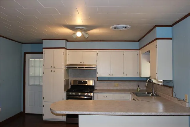 a kitchen with stainless steel appliances a stove and white cabinets