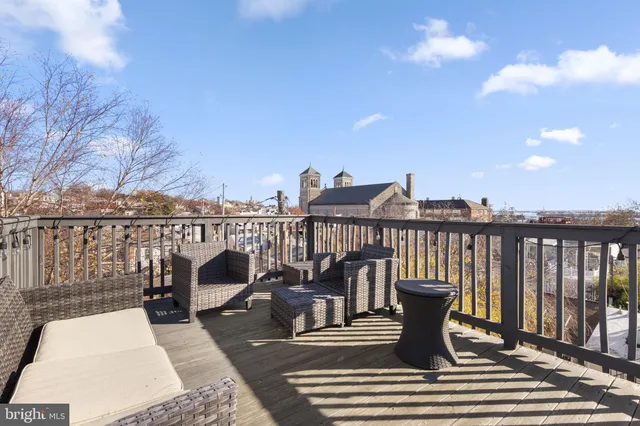 a view of a balcony with wooden chairs and floor to ceiling window
