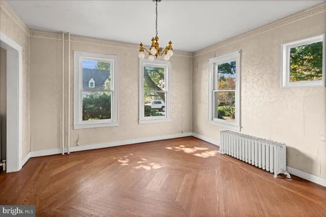 a view of an empty room with window and wooden floor