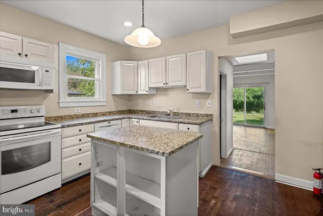 a kitchen with granite countertop white cabinets and window