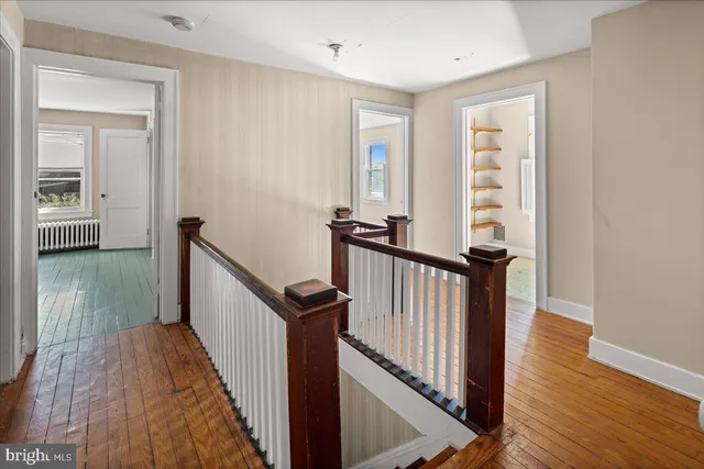 a view of a hallway with wooden floor and stairs