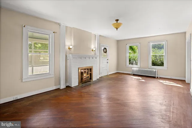 an empty room with windows and fireplace