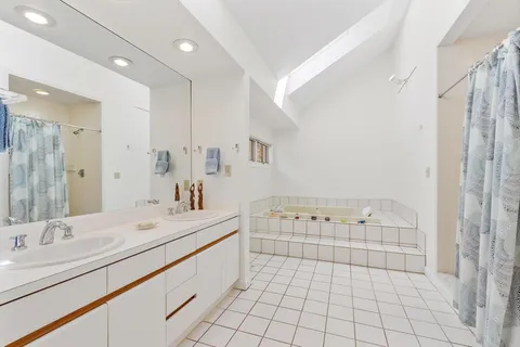 a spacious bathroom with a double vanity sink a mirror and a bathtub