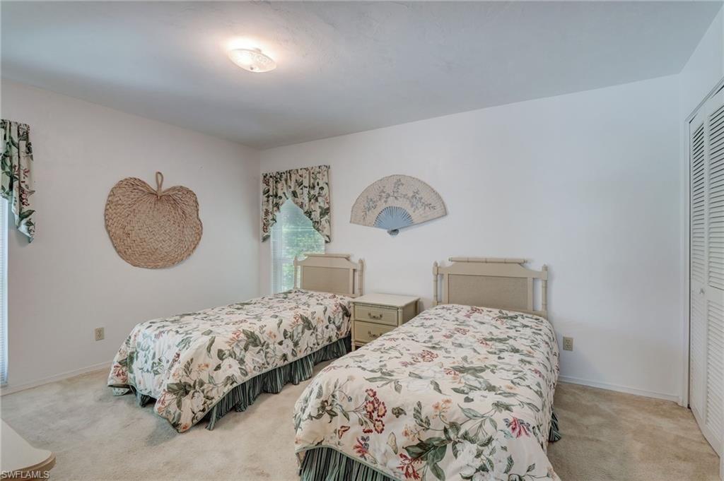 115 Georgetown Boulevard, Unit 115 Naples, FL 34112 - Photo 18 of 45 a bedroom with two beds and a chandelier