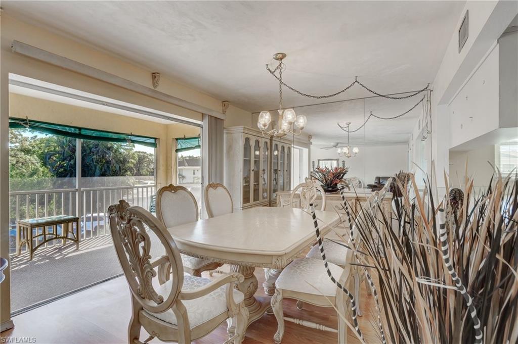 115 Georgetown Boulevard, Unit 115 Naples, FL 34112 - Photo 9 of 45 a dining room with furniture a chandelier and wooden floor