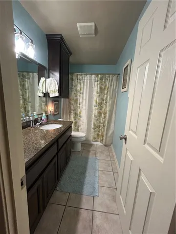 a bathroom with a granite countertop sink a toilet a mirror and vanity