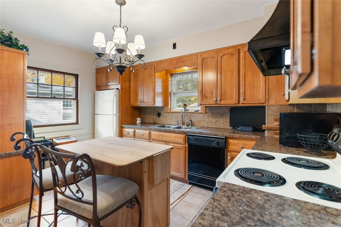 3521 Hopkins Road Youngstown, OH 44511 - Photo 12 of 31 Kitchen with white appliances, tasteful backsplash, light tile patterned floors, exhaust hood, and an inviting chandelier