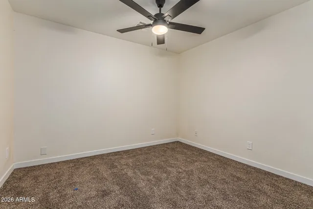 an empty room with a fan and a window