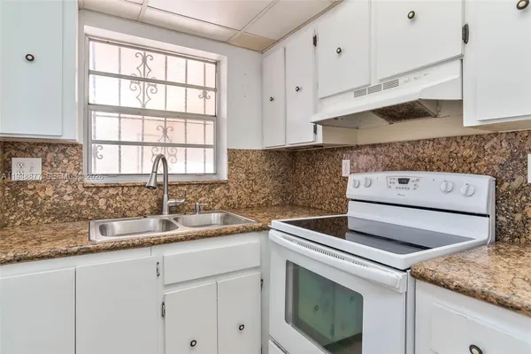 a kitchen with granite countertop white cabinets and a sink
