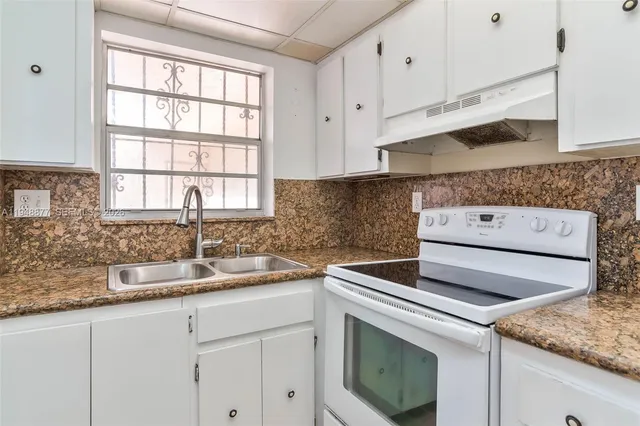 a kitchen with granite countertop white cabinets and a sink