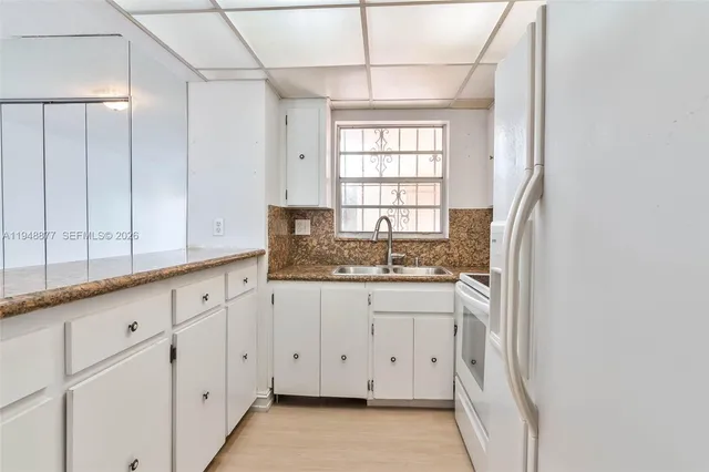 a kitchen with granite countertop white cabinets and a sink