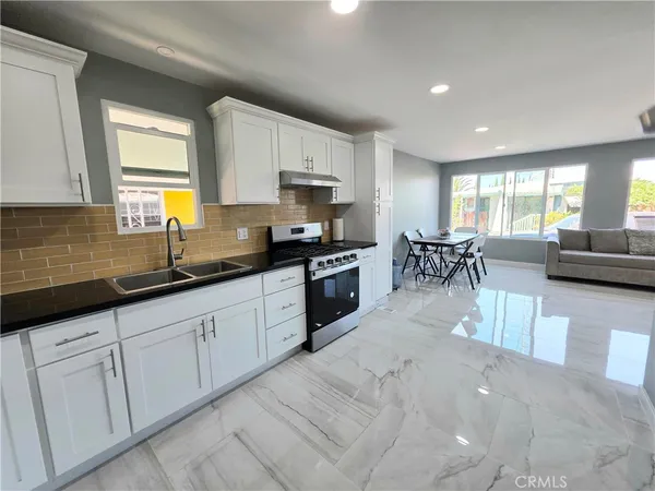 a kitchen with white cabinets and sink