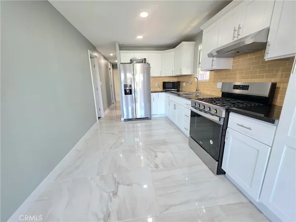 a large kitchen with stainless steel appliances granite countertop a stove and a refrigerator