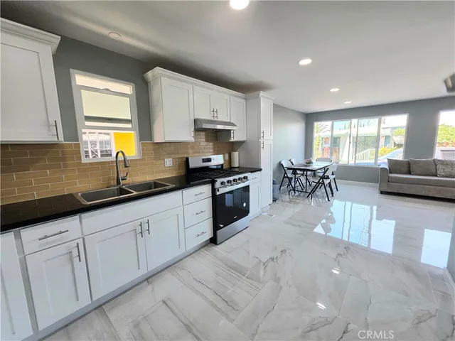 a kitchen with white cabinets and sink