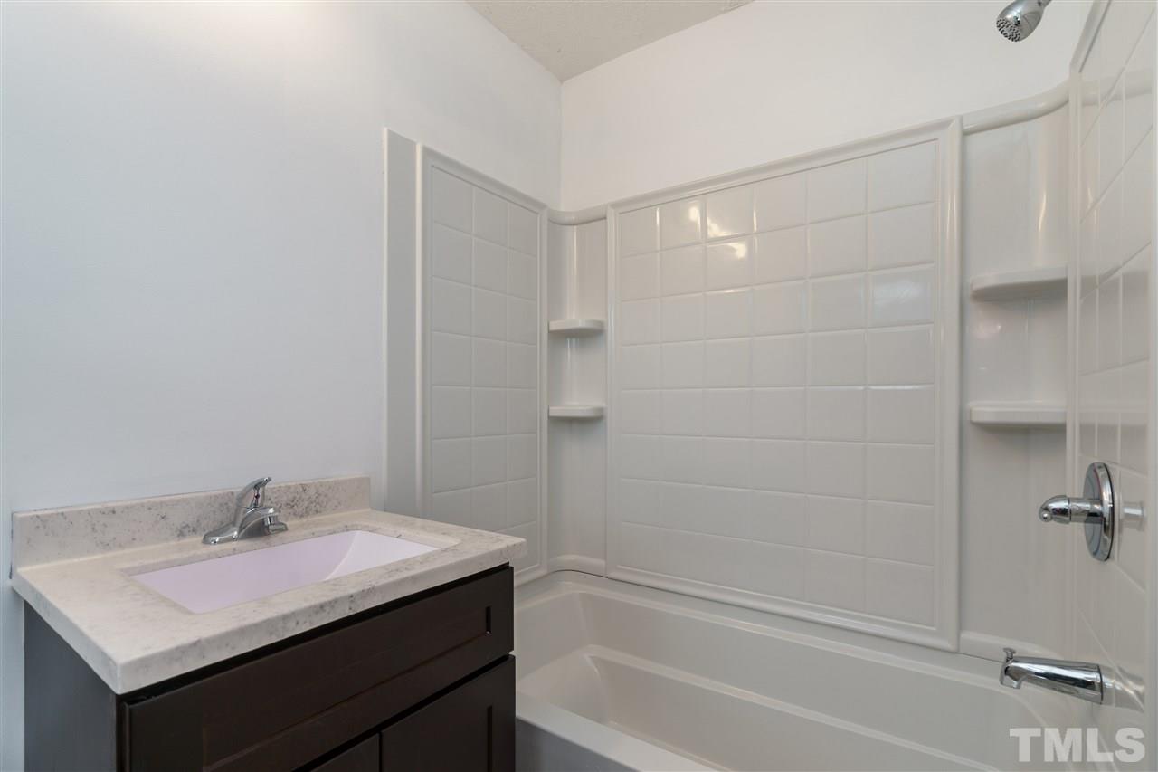 1421 Creech Road Garner, NC 27529 - Photo 22 of 23 a bathroom with a granite countertop sink mirror toilet and bathtub