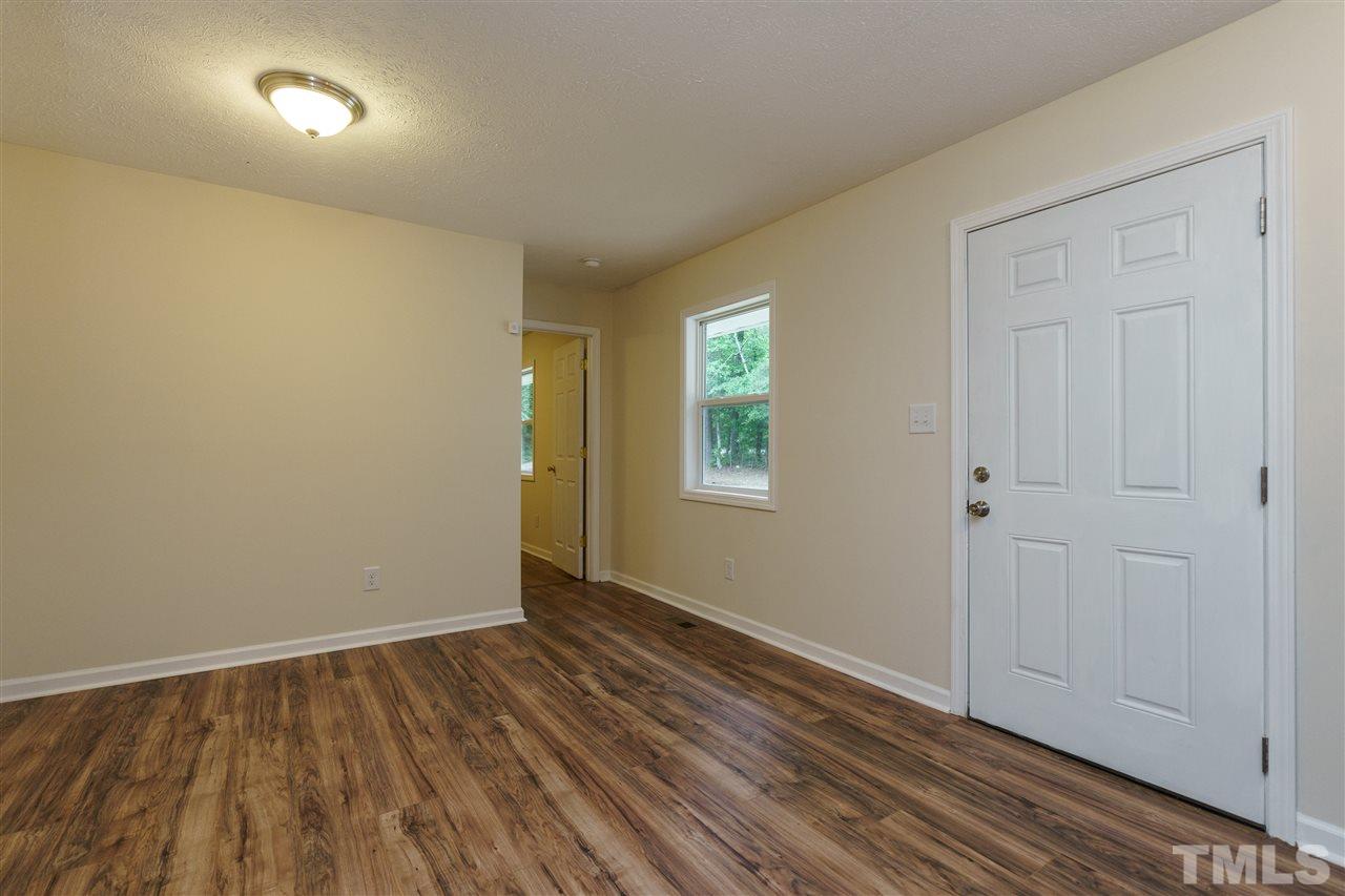 1421 Creech Road Garner, NC 27529 - Photo 4 of 23 a view of an empty room with wooden floor and a window