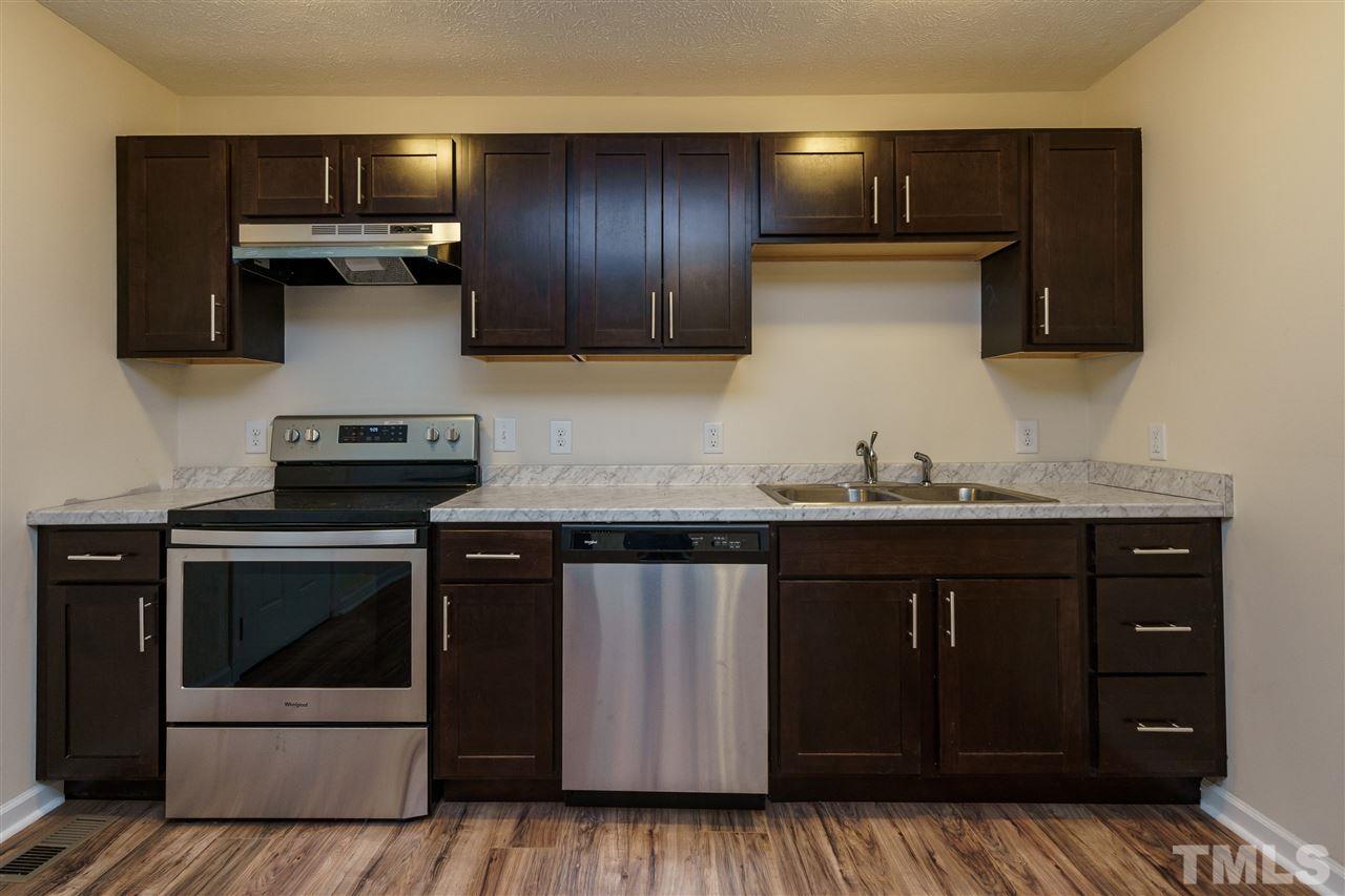 1421 Creech Road Garner, NC 27529 - Photo 8 of 23 a kitchen with stainless steel appliances granite countertop wooden cabinets and a stove top oven