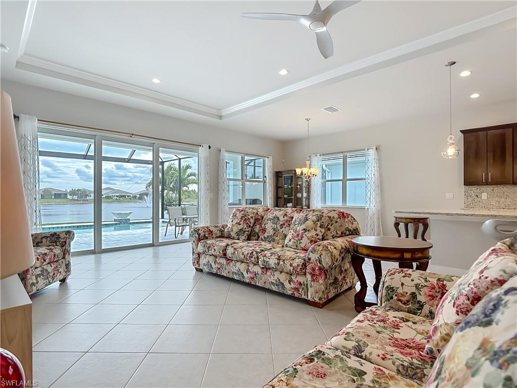 8980 Mustique Lane Naples, FL 34114 - Photo 24 of 50 Living area with light tile patterned floors, a tray ceiling, recessed lighting, a ceiling fan, and a water view