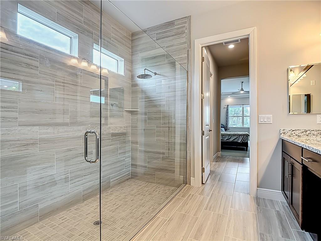 8980 Mustique Lane Naples, FL 34114 - Photo 29 of 50 Bathroom with connected bathroom, vanity, a shower stall, and a ceiling fan