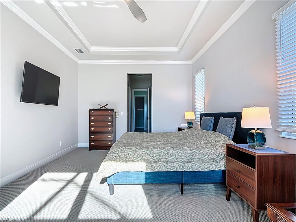 8980 Mustique Lane Naples, FL 34114 - Photo 30 of 50 Bedroom featuring a raised ceiling, carpet floors, ornamental molding, and a ceiling fan