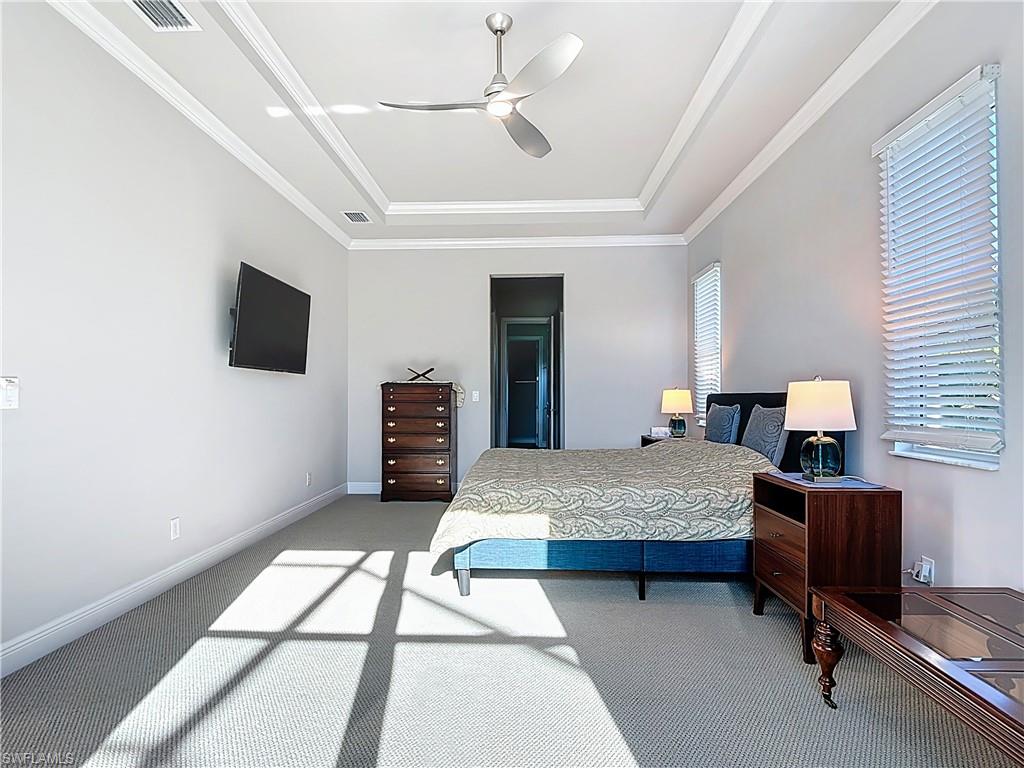 8980 Mustique Lane Naples, FL 34114 - Photo 31 of 50 Bedroom featuring light colored carpet, a raised ceiling, crown molding, and a ceiling fan