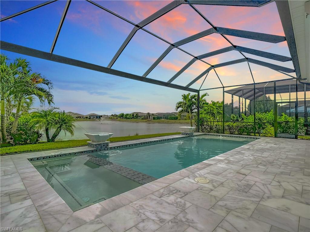 8980 Mustique Lane Naples, FL 34114 - Photo 36 of 50 View of pool with a sunroom, a lanai, a water view, a pool with connected hot tub, and a patio