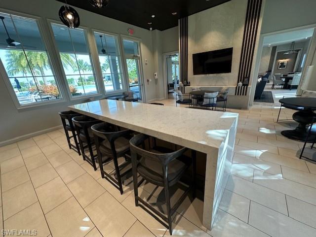 8980 Mustique Lane Naples, FL 34114 - Photo 50 of 50 Kitchen featuring hanging light fixtures, light stone countertops, a breakfast bar area, and open floor plan