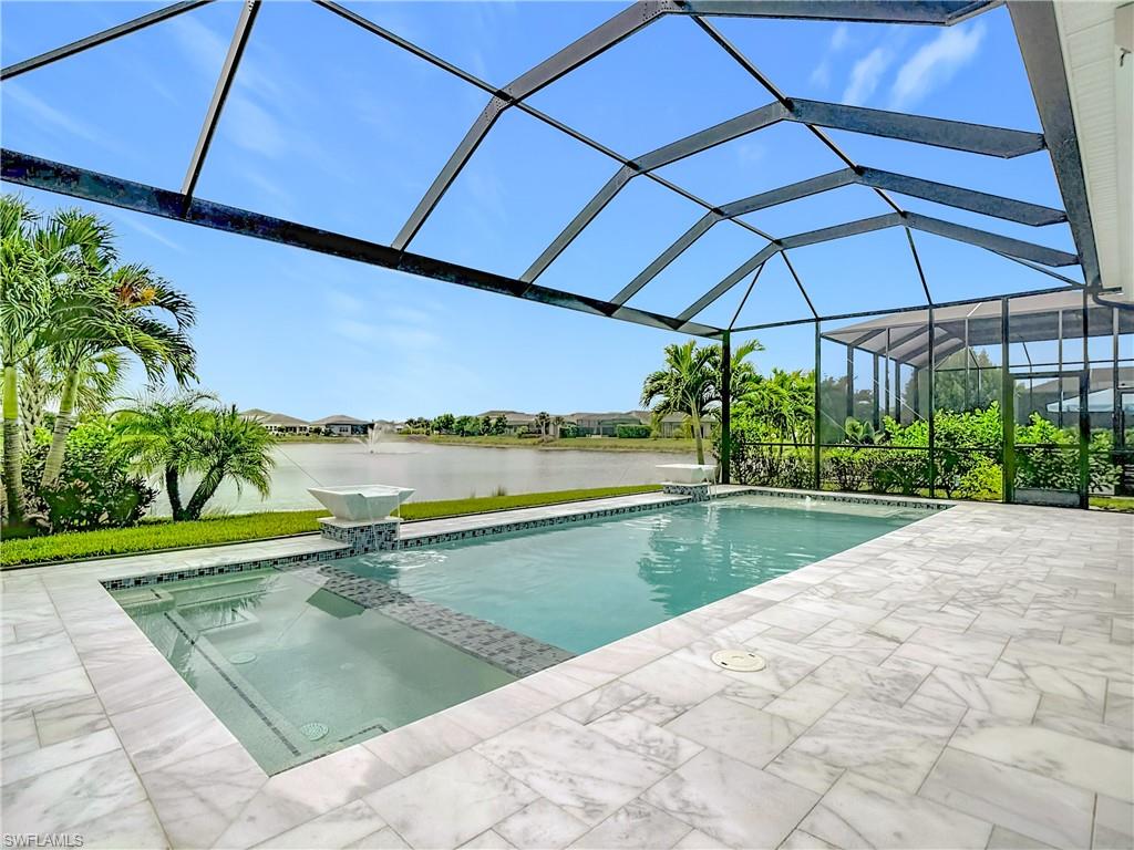 8980 Mustique Lane Naples, FL 34114 - Photo 5 of 50 View of swimming pool featuring a water view, a pool with connected hot tub, and a patio area