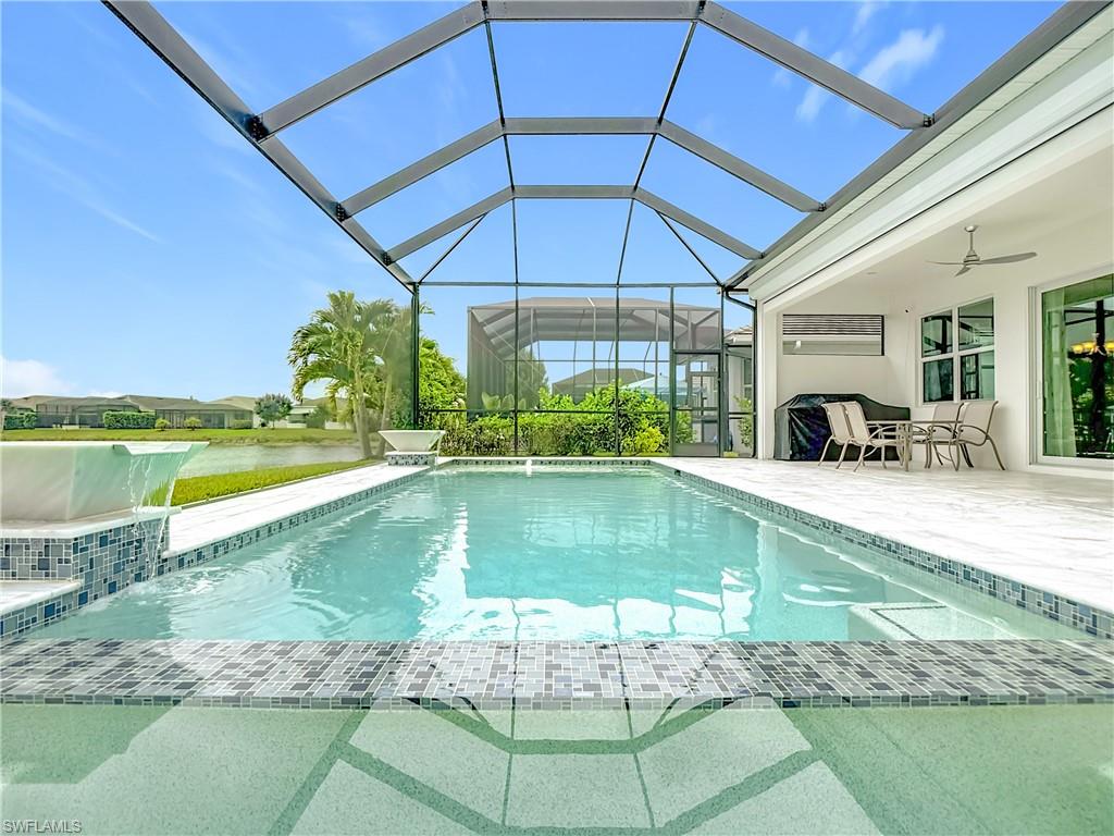 8980 Mustique Lane Naples, FL 34114 - Photo 7 of 50 Outdoor pool featuring a ceiling fan, a patio area, a water view, and a lanai