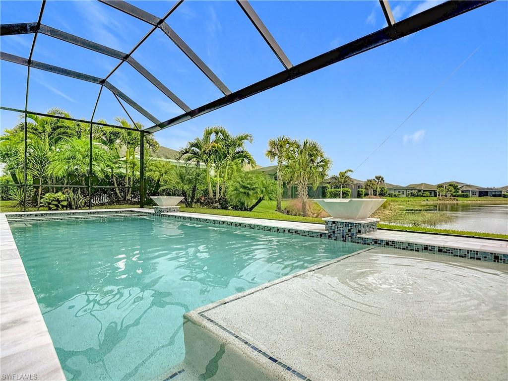 8980 Mustique Lane Naples, FL 34114 - Photo 9 of 50 Swimming pool featuring a sunroom, a lanai, a patio area, and a water view