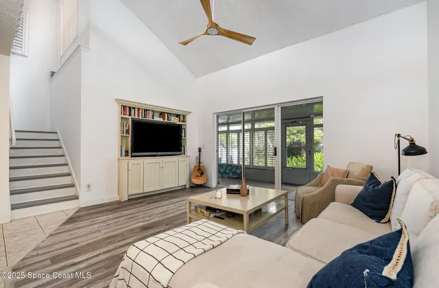 a living room with furniture a flat screen tv and a floor to ceiling window