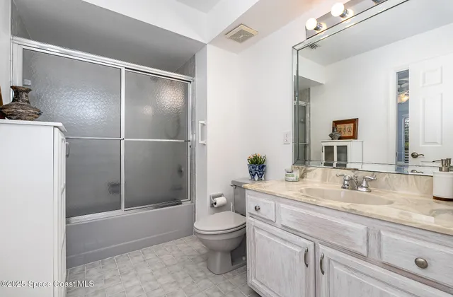 a bathroom with a granite countertop sink a toilet and shower