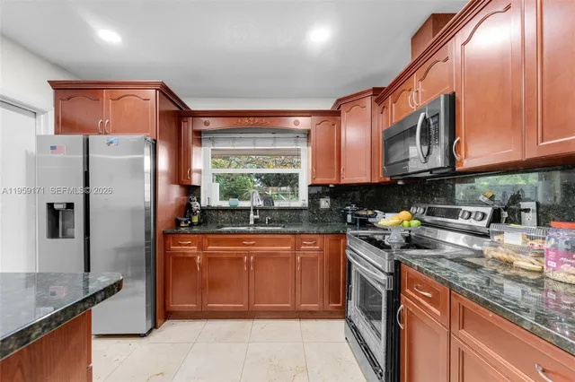 a kitchen with stainless steel appliances granite countertop a refrigerator a sink a stove top oven and a dishwasher
