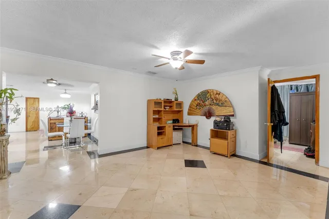 a view of a livingroom with workspace and a ceiling fan