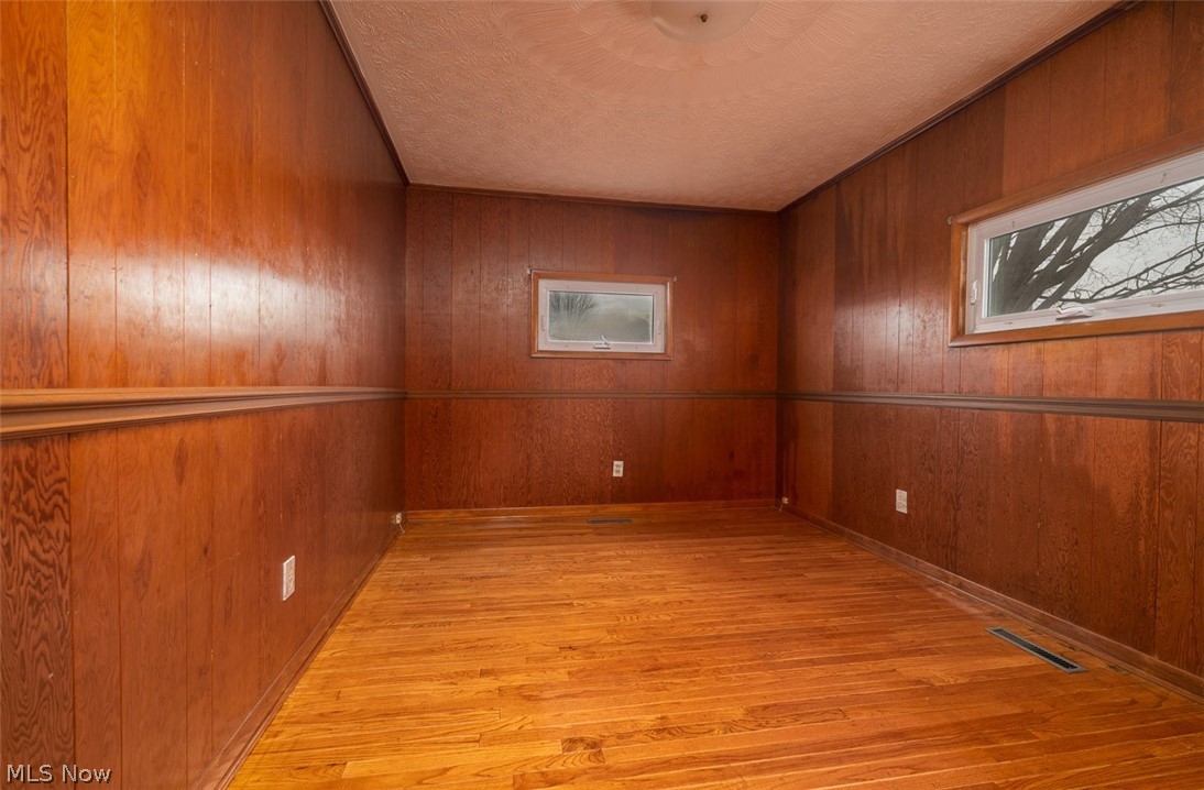 3336 Broad Run Dairy Road Northwest Dover, OH 44622 - Photo 25 of 26 Empty room featuring light wood-style flooring, wood walls, and a textured ceiling
