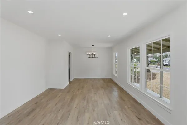 an empty room with wooden floor chandelier and windows
