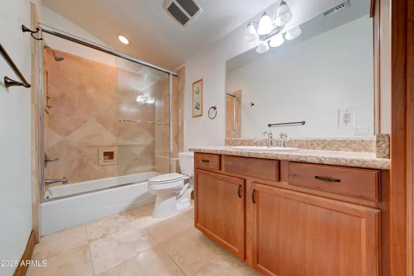 a bathroom with a granite countertop sink a toilet and shower