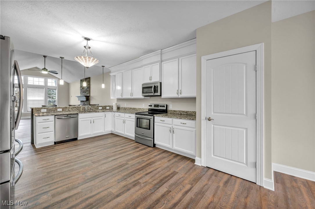 10020 Fair Road Strongsville, OH 44149 - Photo 13 of 47 Kitchen with white cabinets, stainless steel appliances, a peninsula, decorative light fixtures, and vaulted ceiling