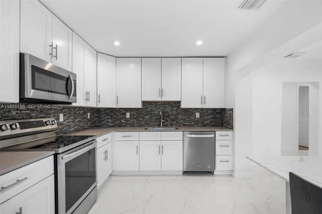 a kitchen with stainless steel appliances granite countertop a stove a microwave and a sink