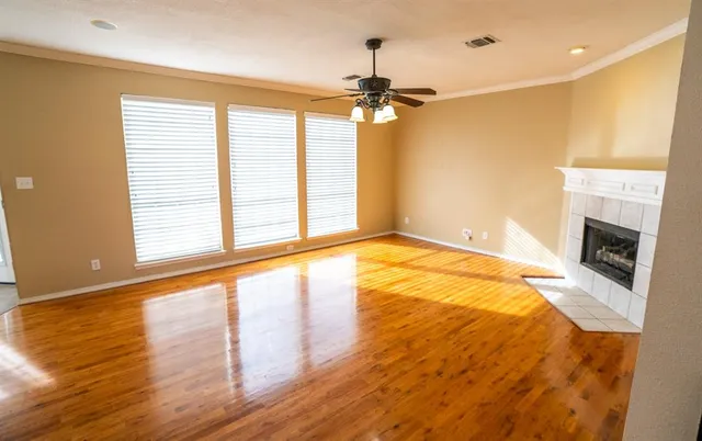a view of an empty room with a window and wooden floor