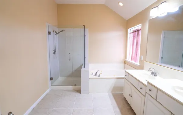 a spacious bathroom with a tub sink shower and mirror