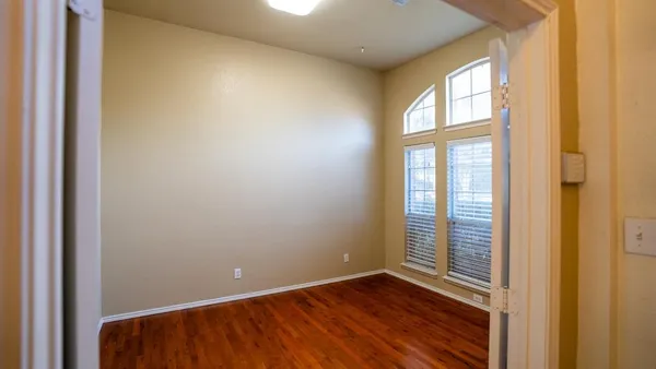 a view of an empty room with wooden floor and a window