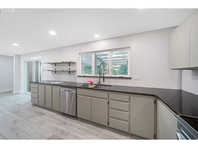 a kitchen with stainless steel appliances granite countertop a sink window and cabinets