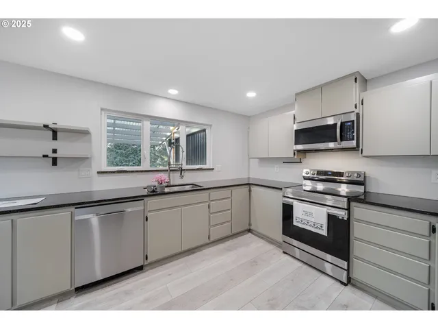 a kitchen with stainless steel appliances granite countertop a stove a sink and a microwave