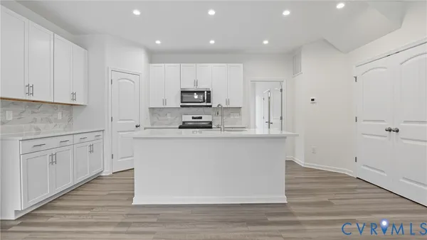 a kitchen with kitchen island white cabinets and stainless steel appliances