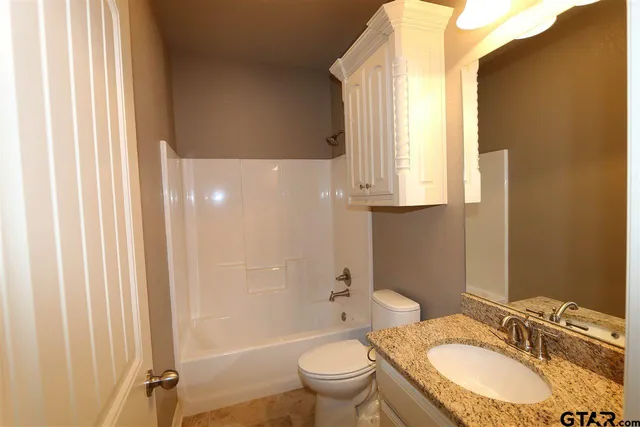 a bathroom with a granite countertop sink toilet and shower